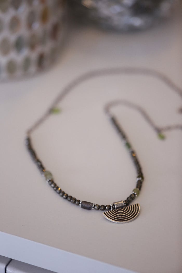 Elegant silver beaded necklace with a spiral pendant on a white background.